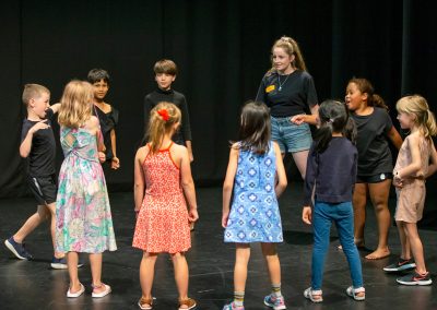 Photo of children rehearsing with a teacher on stage