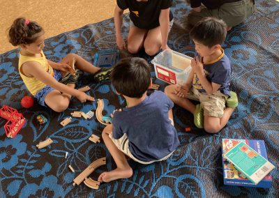 EC students and tutors on a mat surrounded by toys