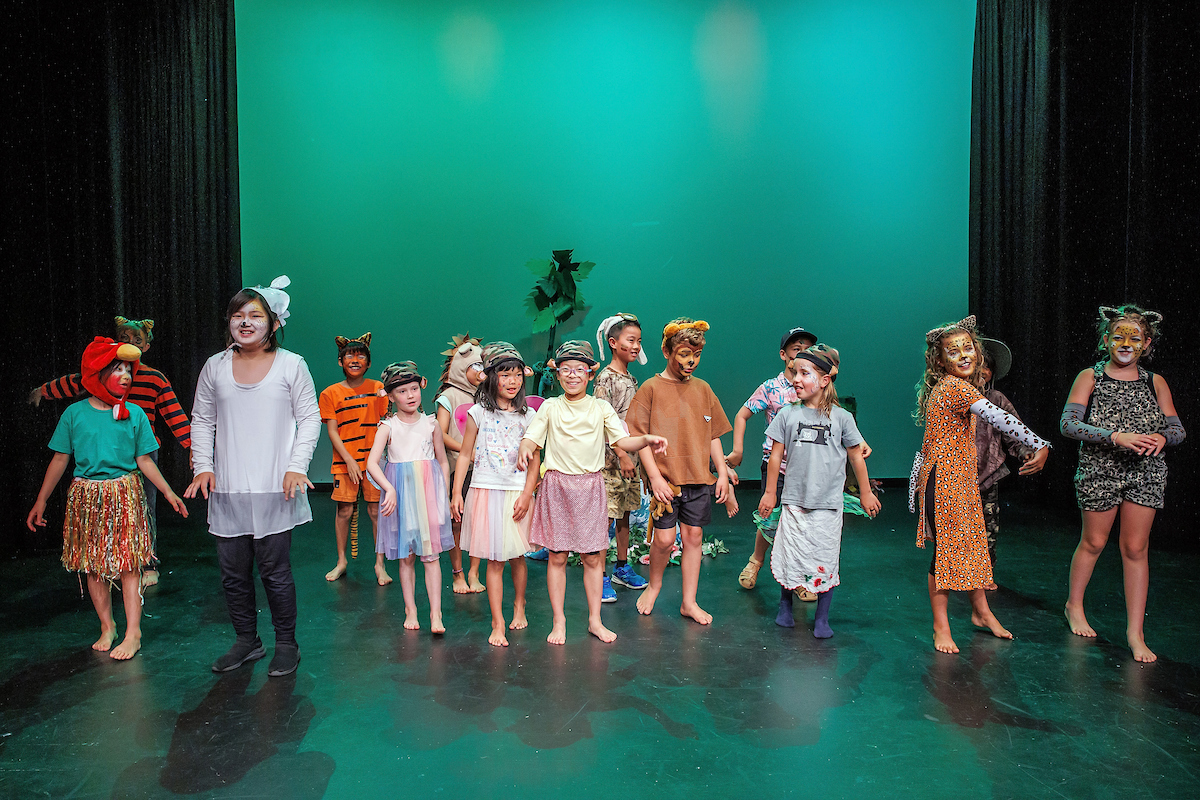 Children and one adult on stage with green backdrop at The Rose Centre