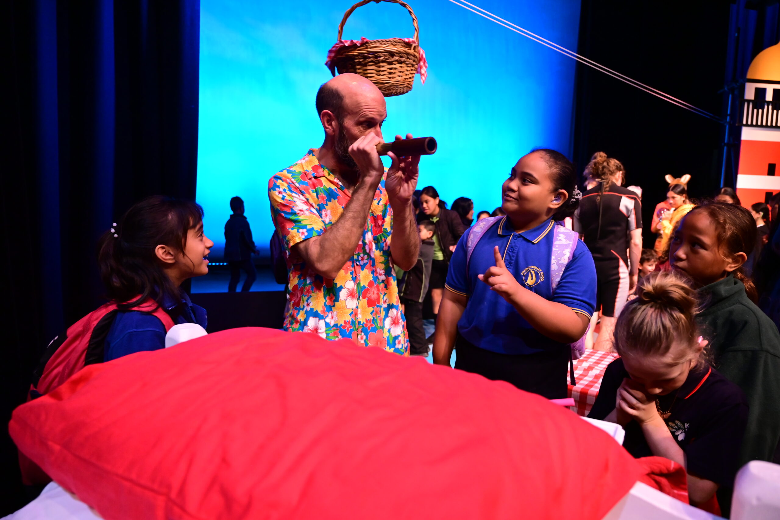 Man holding telescope and children with red blanket in front